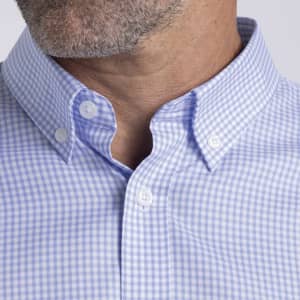 A close-up of a light blue checkered button-up shirt collar with a subtle logo.