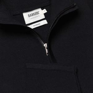 A navy Merino shirt with a zip neck and front pocket, featuring a brand label inside.