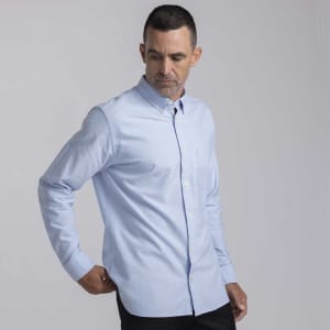 A light blue button-up shirt for men, featuring a collar and a chest pocket, with a logo on the fabric.