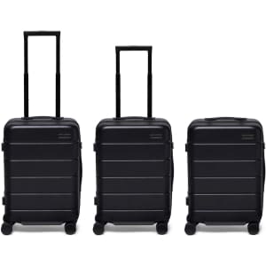 Three black hardcase suitcases with extendable handles and wheels, featuring a logo on the front.