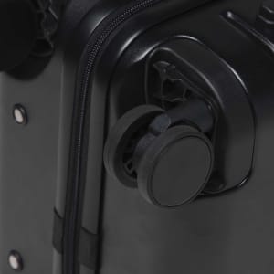 A close-up of a black hardcase trolley with a wheel and zipper detail. The product features a logo.
