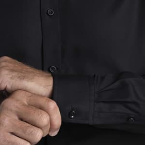 A black button-up shirt featuring long sleeves and stylish cuffs. It has a logo on the fabric.