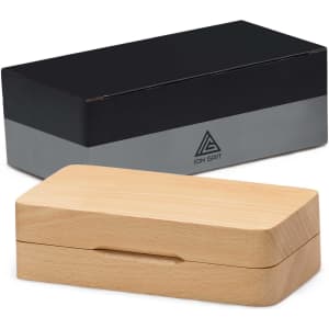 A wooden box in a light colour, featuring a dark lid and a logo, designed for storing a product.