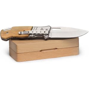 A pocket knife with a silver blade and a wooden handle, resting on a light wooden box.
