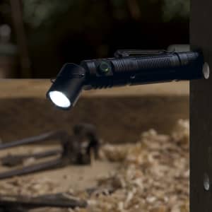A black FlexLight Torch is mounted on a wooden surface, emitting a bright light. It features a clip and a logo.