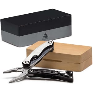 A black and silver multi-tool with pliers, displayed partly open next to a wooden box and a sleek black packaging.