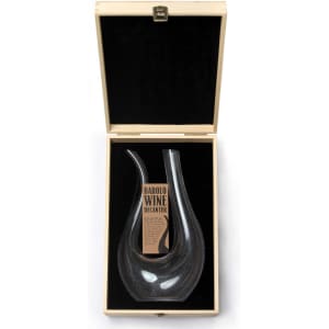 A sleek black glass decanter displayed in a wooden box with a black velvet lining. It features a branding logo.