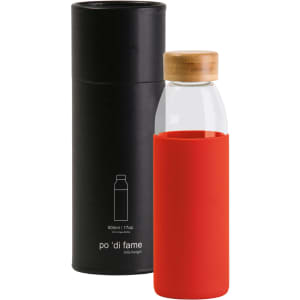 A drink bottle with a clear glass body, red silicone sleeve, and bamboo lid, accompanied by a black cylindrical container.