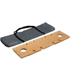 A bamboo table in a grey carrying bag, featuring two circular cutouts and interlocking sections.