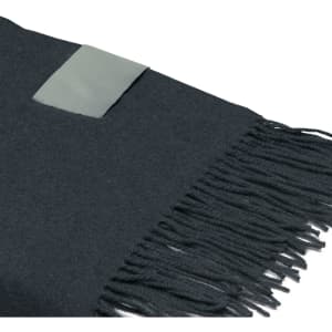 A black Merino blanket with fringed edges and a branding label on one corner.