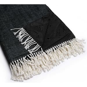 A green and black picnic blanket with a herringbone pattern and white fringes, featuring a water-resistant corner.
