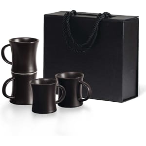 A black Quartetto Espresso Set featuring four espresso mugs stacked and packaged in a black gift box with a handle.