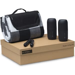 A black and white checkered blanket, two black speakers, and two black markers on a brown box.