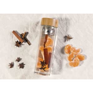 A drink bottle with a bamboo lid, filled with citrus slices, cinnamon sticks, and star anise. Features a logo.