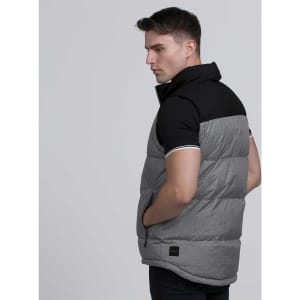A man wearing a grey and black sleeveless vest with a high collar, featuring a logo on the side.