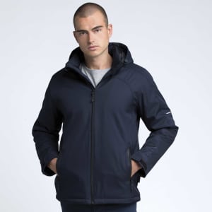 A model wearing a navy blue soft shell jacket with a hood, featuring a branded logo on the sleeve.