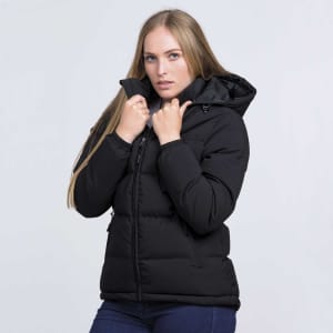 A black puffer jacket with a hood, featuring a zip and front pockets, modelled by a woman.