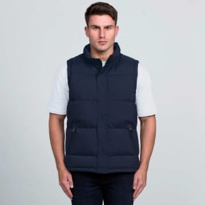 A navy puffa vest with a high collar, featuring zippered pockets and a logo. Worn by a model against a neutral background.