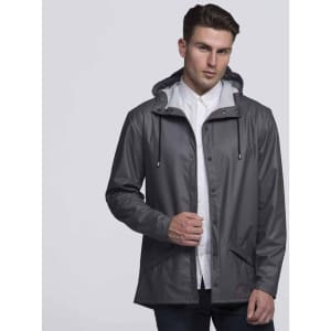 A man in a grey rain jacket with a hood and drawstrings stands against a plain background. The jacket features pockets and a logo.