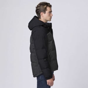 A side view of a man wearing a black and grey smpli XT Plunge Jacket, featuring a hood and a branded logo.