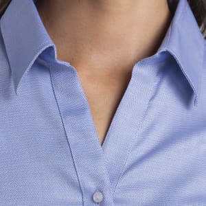 A blue button-up shirt with a collar and a textured fabric, featuring a logo on the chest area.