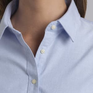 A light blue button-up shirt with a collar and two buttons at the neckline, featuring a logo on the chest.