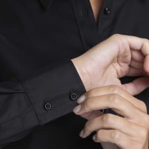 A black button-up shirt featuring a close-up of the cuff and buttons.