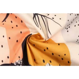 A close-up of fabric featuring a vibrant pattern with peach, orange, black, and cream colours, showcasing a light texture.