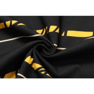 Cotton fabric featuring a black background with yellow and beige graphic patterns.