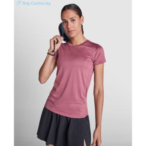 A pink women's T-shirt made from moisture-wicking fabric, paired with a black skirt, featuring a logo.
