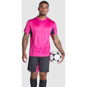 A sports uniform set in vibrant pink and black, featuring a shirt and shorts, held by a model with a soccer ball.
