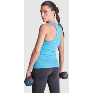 A woman in a blue tank top holds dumbbells, showcasing the back design while standing against a plain background.