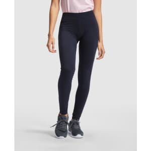 Navy leggings featured, paired with a light pink top and grey athletic shoes. The image has a branding logo.