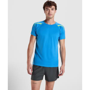A blue T-shirt with yellow accents, worn by a model, features short sleeves and a logo.