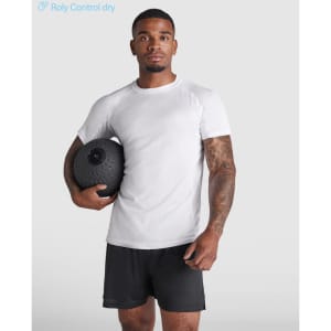 A man wearing a white Montecarlo T-shirt and black shorts holds a fitness ball, posing against a light background.