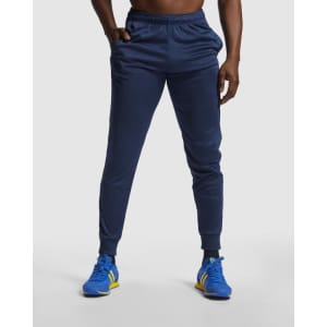 Navy track pants with a fitted design, featuring an elastic waistband and cuffs. The model wears sporty shoes.