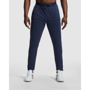 Navy track pants with a drawstring waist, featuring a logo on the side, styled with white sneakers.