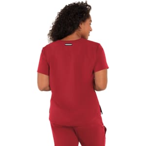 A woman wearing a red top facing away, showcasing the back design. The top has a subtle branding detail.