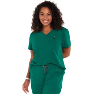 A green short-sleeve top with a v-neck and a pocket, worn by a smiling woman with curly hair.