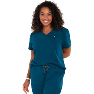 A teal women's top with a V-neck, short sleeves, and a pocket, worn with matching pants. The model has curly hair.