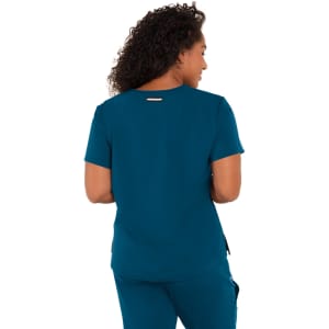 A woman wearing a teal top, viewed from the back, with a logo on the garment.