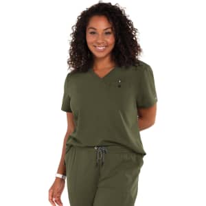 A woman smiles while wearing a green "Ready to Work Top" with a pocket and a logo. The fabric appears comfortable.