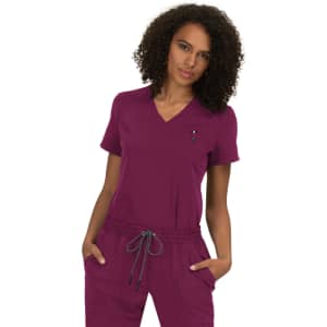 A woman is wearing a purple scrubs top with a v-neckline and short sleeves, featuring a front pocket and drawstring waist.