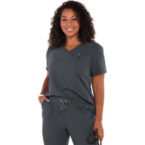 A woman wearing a grey top paired with grey pants, featuring a logo and a stylish, comfortable design.