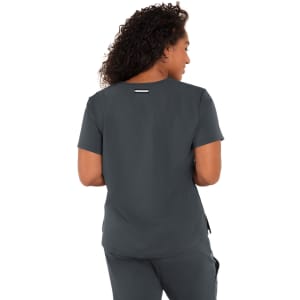A woman with curly hair wearing a dark grey short-sleeve top, viewed from the back. The top has a logo.