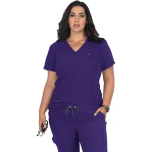 A purple medical top with a V-neck and short sleeves, featuring a logo. The model poses confidently in scrubs.