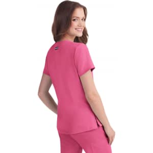 A woman in a pink top stands, smiling over her shoulder. The top has short sleeves and a logo on the back.