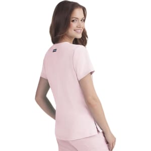 A pink short-sleeved top with a logo on the back, featuring a relaxed fit and side slits for comfort.