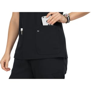 A black top with pockets; a hand holds a phone while another pocket contains a pen. The product features a logo.