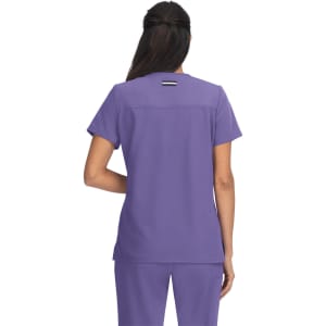 A woman wearing a purple top, viewed from the back, showcasing a simple design with a logo.